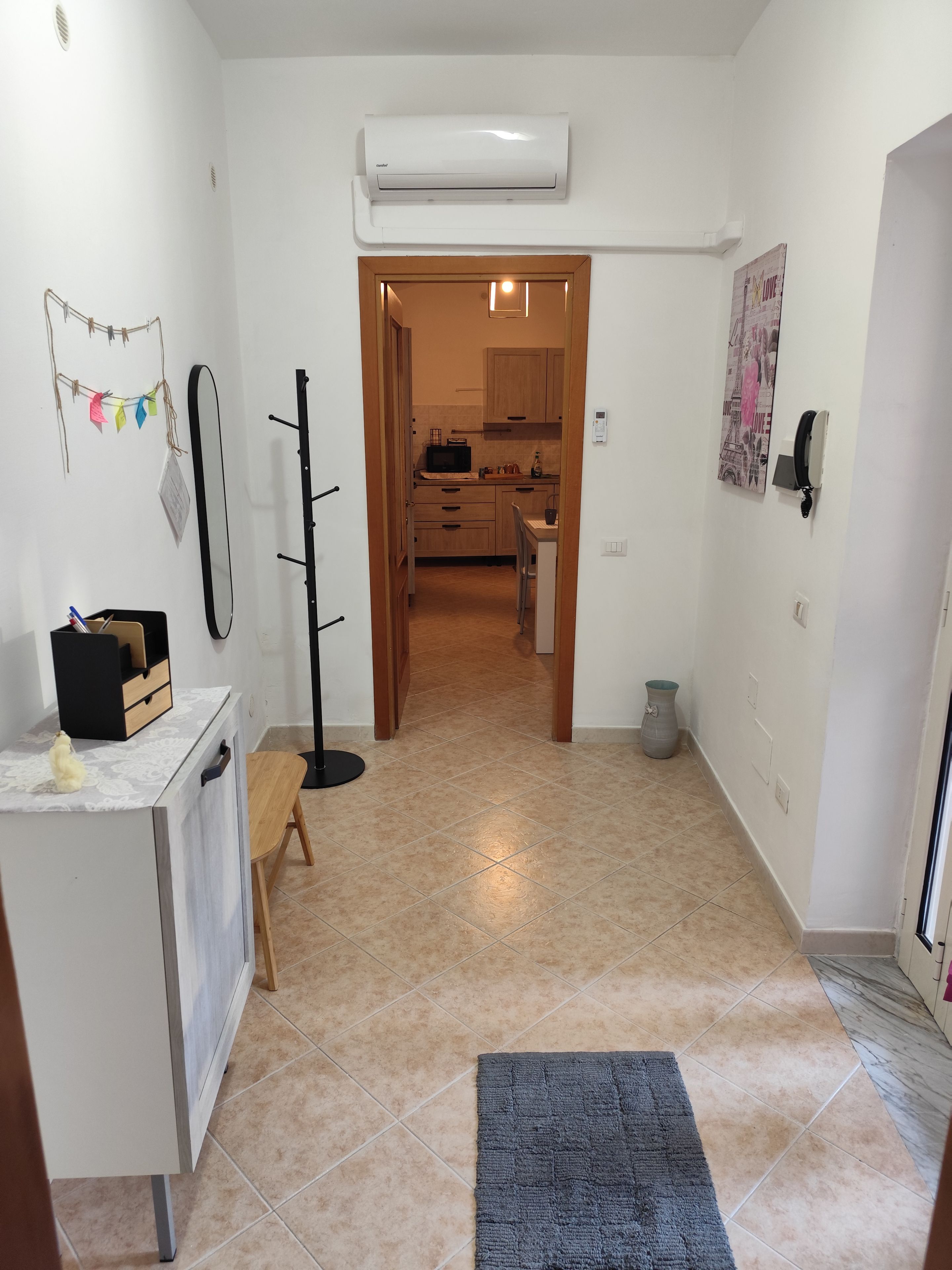 Un couloir mène à une cuisine équipée d’un four à micro-ondes, d’une petite table et d’une chaise.
