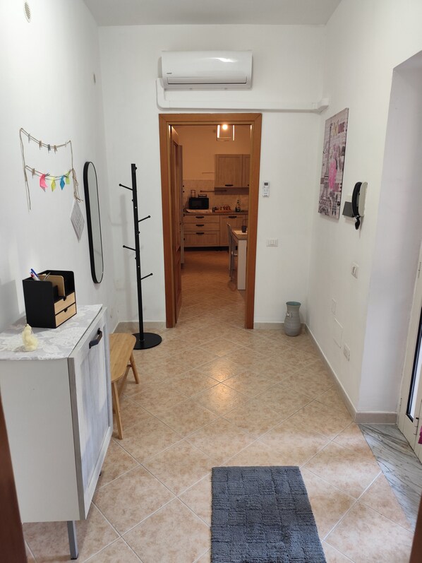 A hallway leading to a kitchen with a microwave, a small table, and a chair.