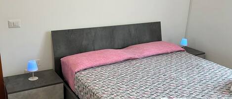 Un dormitorio con cama, mesita de noche, lámpara y decoración en la pared.