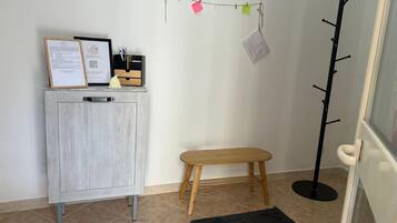 Une pièce avec un meuble en bois, un petit tabouret, un porte-manteau et un tapis noir.