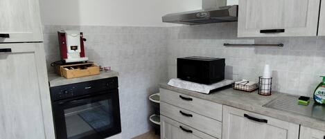 A kitchen with a built-in oven, microwave, and a coffee machine on the countertop.