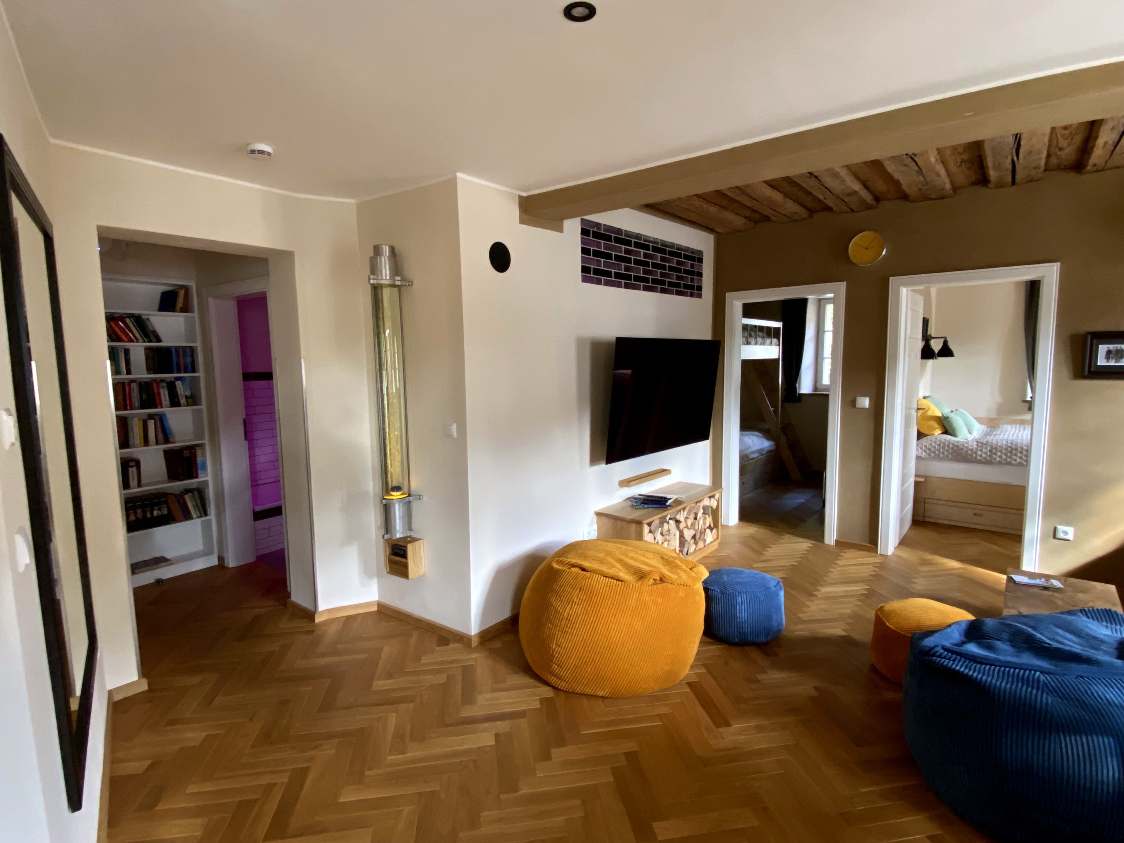 Ein modernes Wohnzimmer mit Fischgrätparkett, einem großen Flachbildfernseher, einem Bücherregal und einem Kamin.