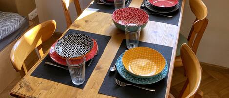 Una mesa de comedor con seis sillas, individuales negros y platos estampados.