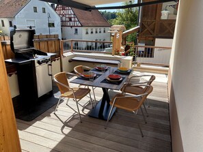 An outdoor patio with a grill, dining table, and chairs. - Our "Loft" vacation suite in the "Schlossberg" vacation home (Betzenstein)