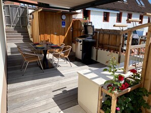 A wooden deck with a table and chairs, a grill, and a wooden fence. - Our "Loft" vacation suite in the "Schlossberg" vacation home (Betzenstein)