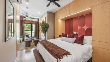 A modern bedroom with a large bed, a ceiling fan, and a view of the outdoors.