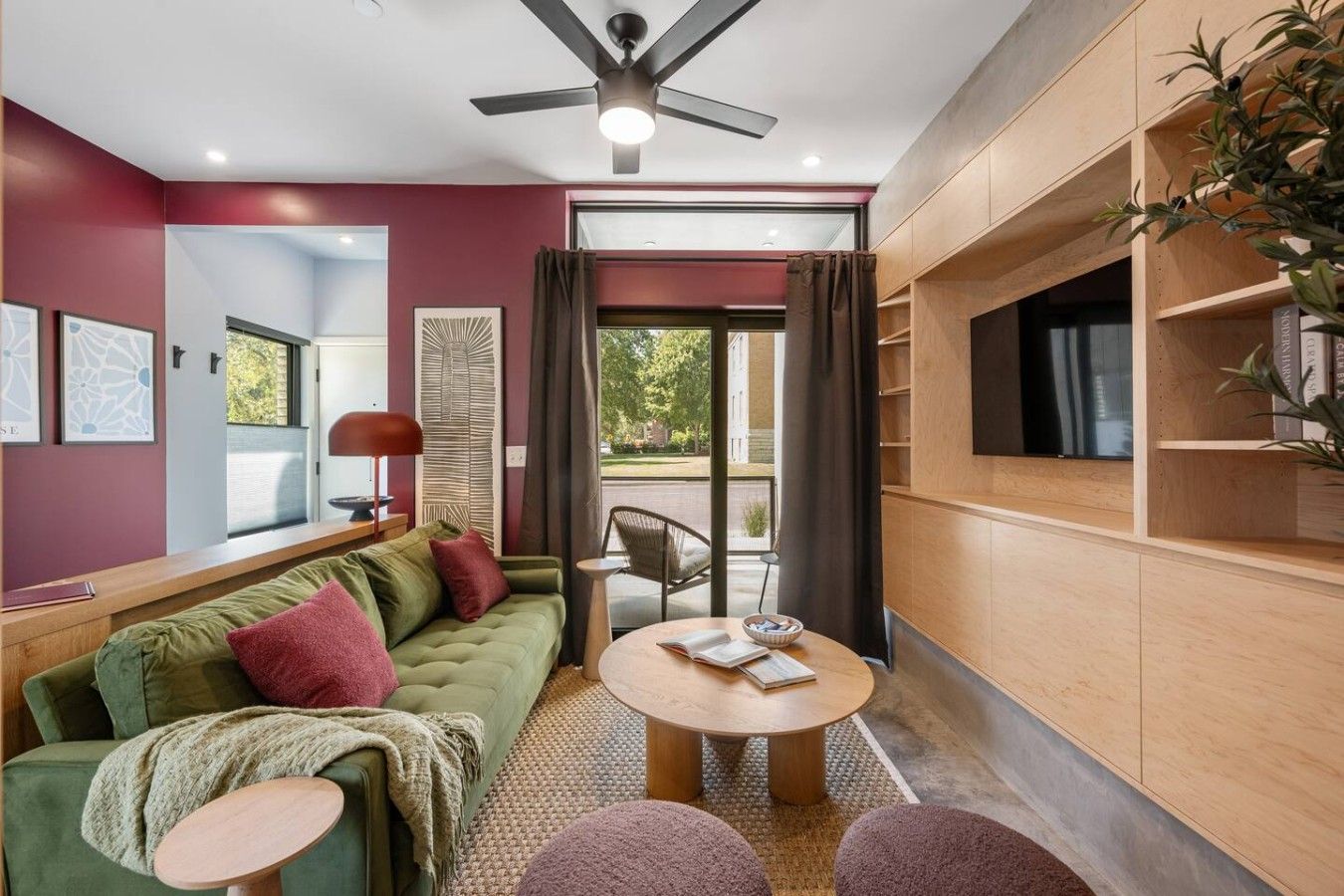 A modern living room with a green sofa, a round coffee table, and a ceiling fan.