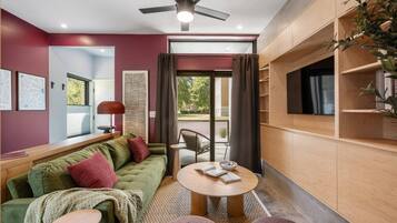 A modern living room with a green sofa, a round coffee table, and a ceiling fan.