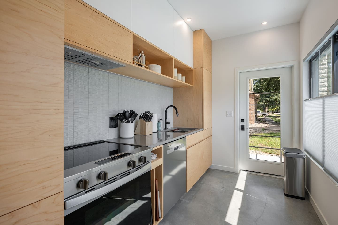 A modern kitchen with a built-in oven, stainless steel appliances, and wooden cabinetry.