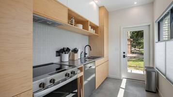 A modern kitchen with a built-in oven, stainless steel appliances, and wooden cabinetry.