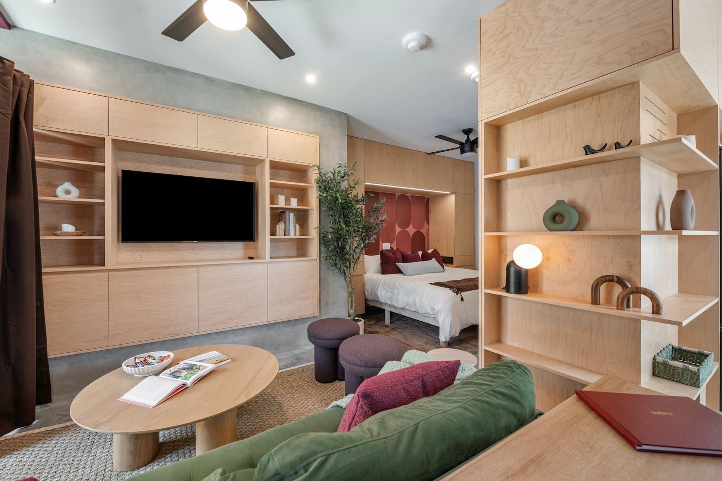 A modern living room with a flat-screen TV, a sofa, a coffee table, and a bookshelf.