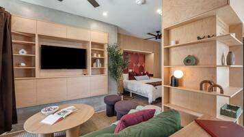 A modern living room with a flat-screen TV, a sofa, a coffee table, and a bookshelf.