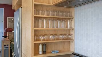 A kitchen with wooden shelves holding glass jars, a kettle, and a bowl.