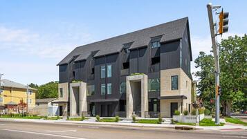 A modern multi-story building with a flat roof, large windows, and a visible address sign.