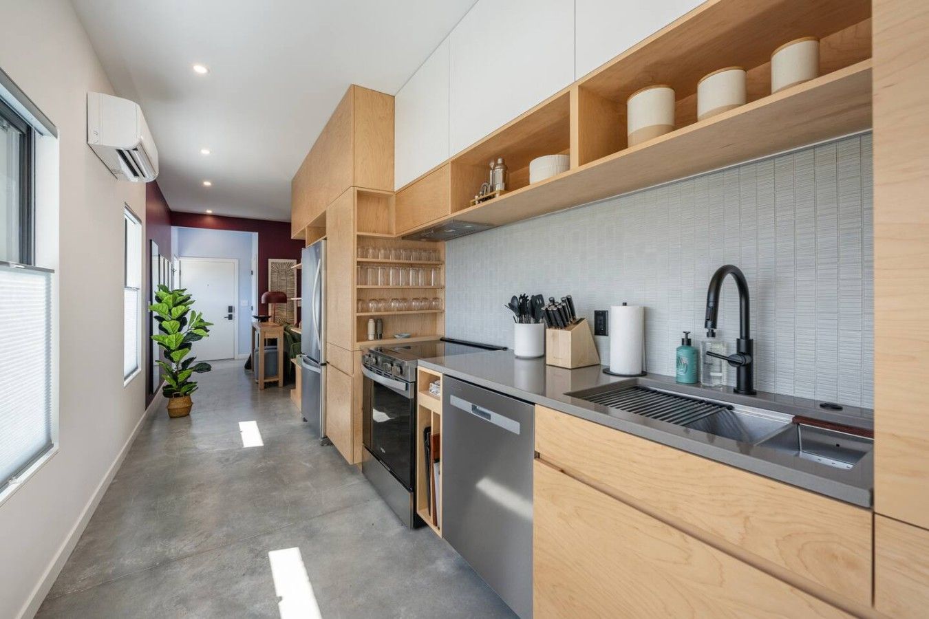 A modern kitchen with built-in appliances, wooden cabinetry, and a stainless steel sink.
