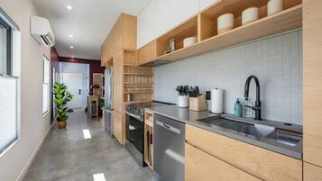 A modern kitchen with built-in appliances, wooden cabinetry, and a stainless steel sink.