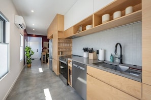 Una cocina moderna con electrodomésticos integrados, muebles de madera y un lavamanos de acero inoxidable.