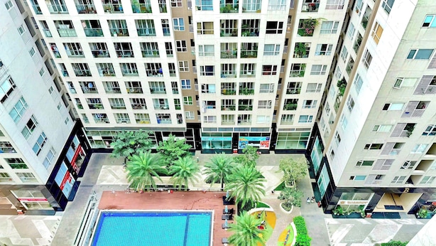 Um edifício residencial alto com várias varandas, um pátio central com piscina e áreas verdes ao redor.