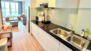 Uma cozinha moderna com bancada preta, pia de aço inoxidável e armários brancos.