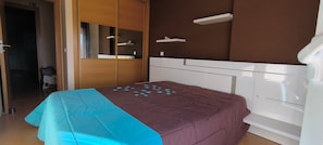 A bedroom with a bed, a wardrobe, and a mirror. - Maison avec piscine privée (Amor)