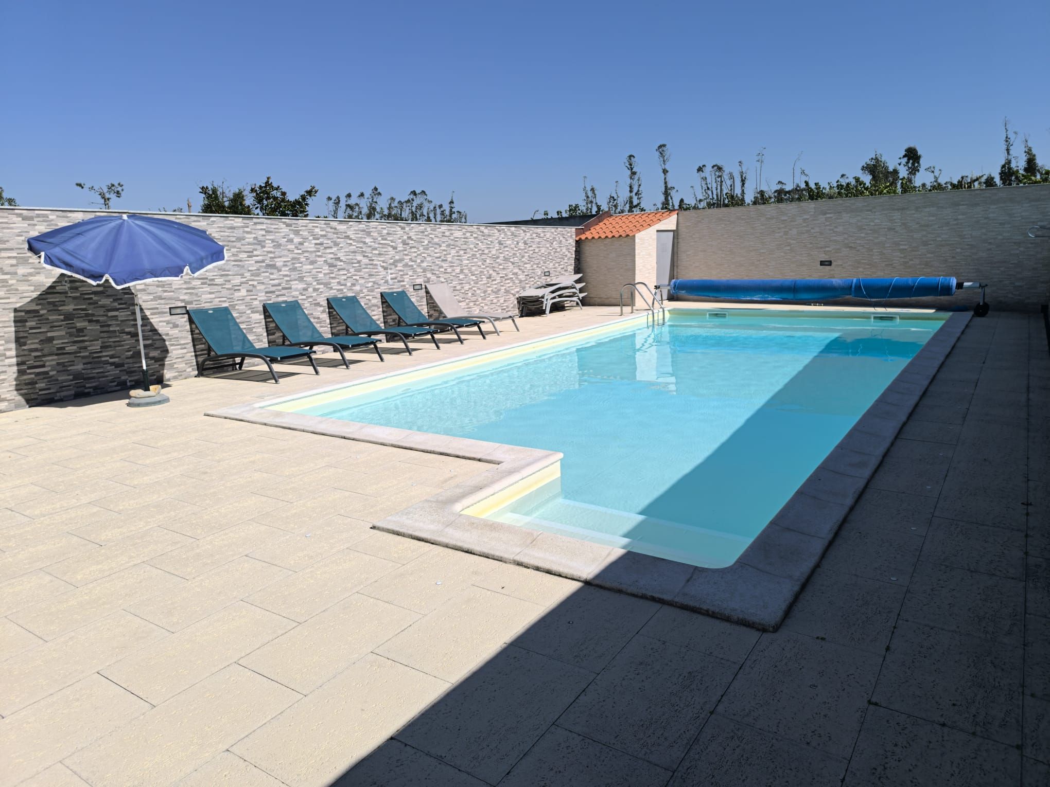 Una piscina amb gandules i un parasol blau.