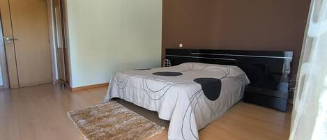 Un dormitorio con una cama, un televisor y piso de madera.