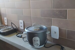 A kitchen with a slow cooker on the counter, a stove, and a wall with electrical outlets. - CASA CHARMOSA (Arraial d'Ajuda)