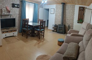 Ein gemütliches Wohnzimmer mit Fernseher, Holztisch und einer Couch.