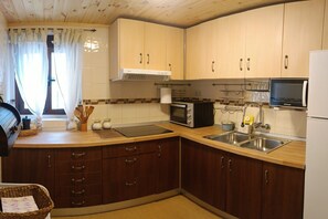 A compact kitchen with wooden cabinets, a microwave, a toaster, and a sink.