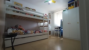 A room with bunk beds, a desk, and a wardrobe.