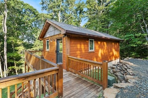 Une cabane en bois dotée d’une terrasse, entourée d’arbres.