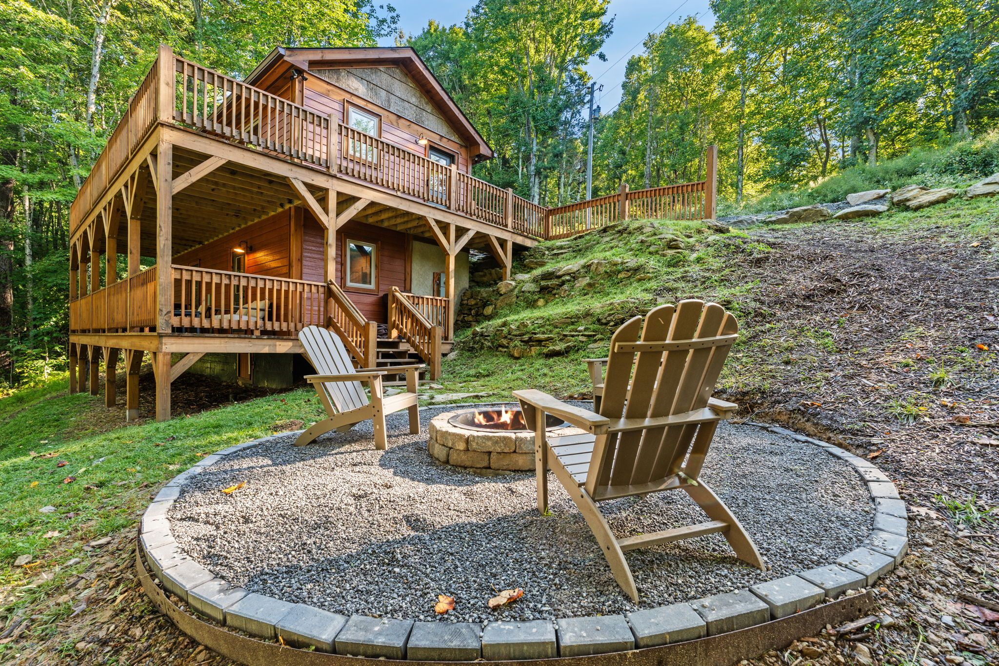 A cabin with a deck, a fire pit, and two Adirondack chairs.