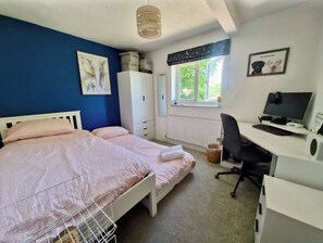 Une chambre à coucher avec un lit, un bureau avec un ordinateur, une fenêtre donnant sur un beau paysage et une armoire.