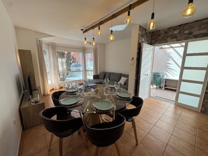 A dining area with a round table, six chairs, and hanging light fixtures. - The Ocean Sur Beach House: A Villa with Ocean Views (Corralejo)