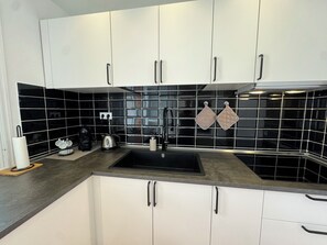 Eine moderne Küche mit weißen Schränken, einer schwarzen Küchenrückwand und einem Edelstahl-Spülbecken.