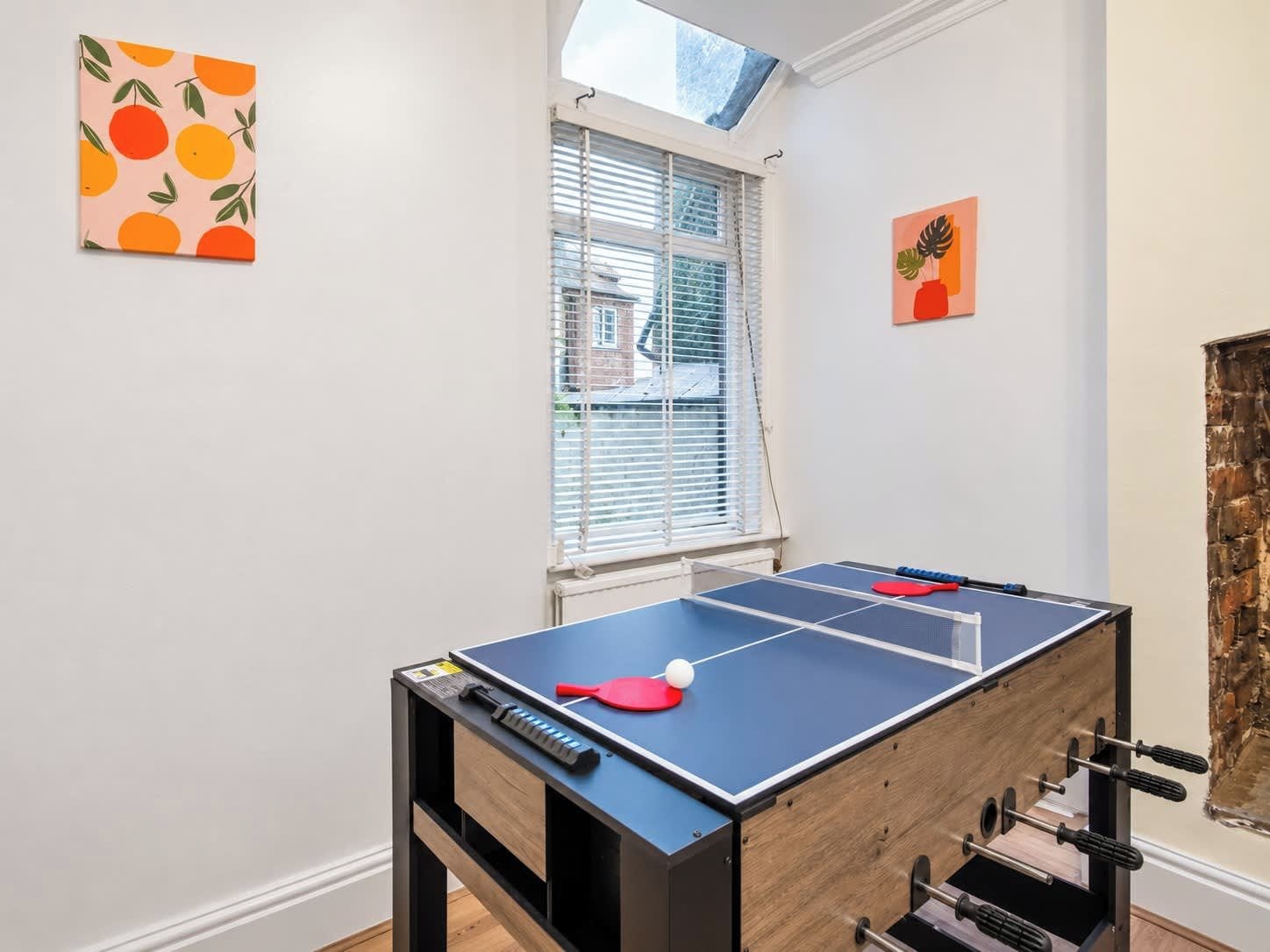 A ping pong table with a blue playing surface and a wooden side table.