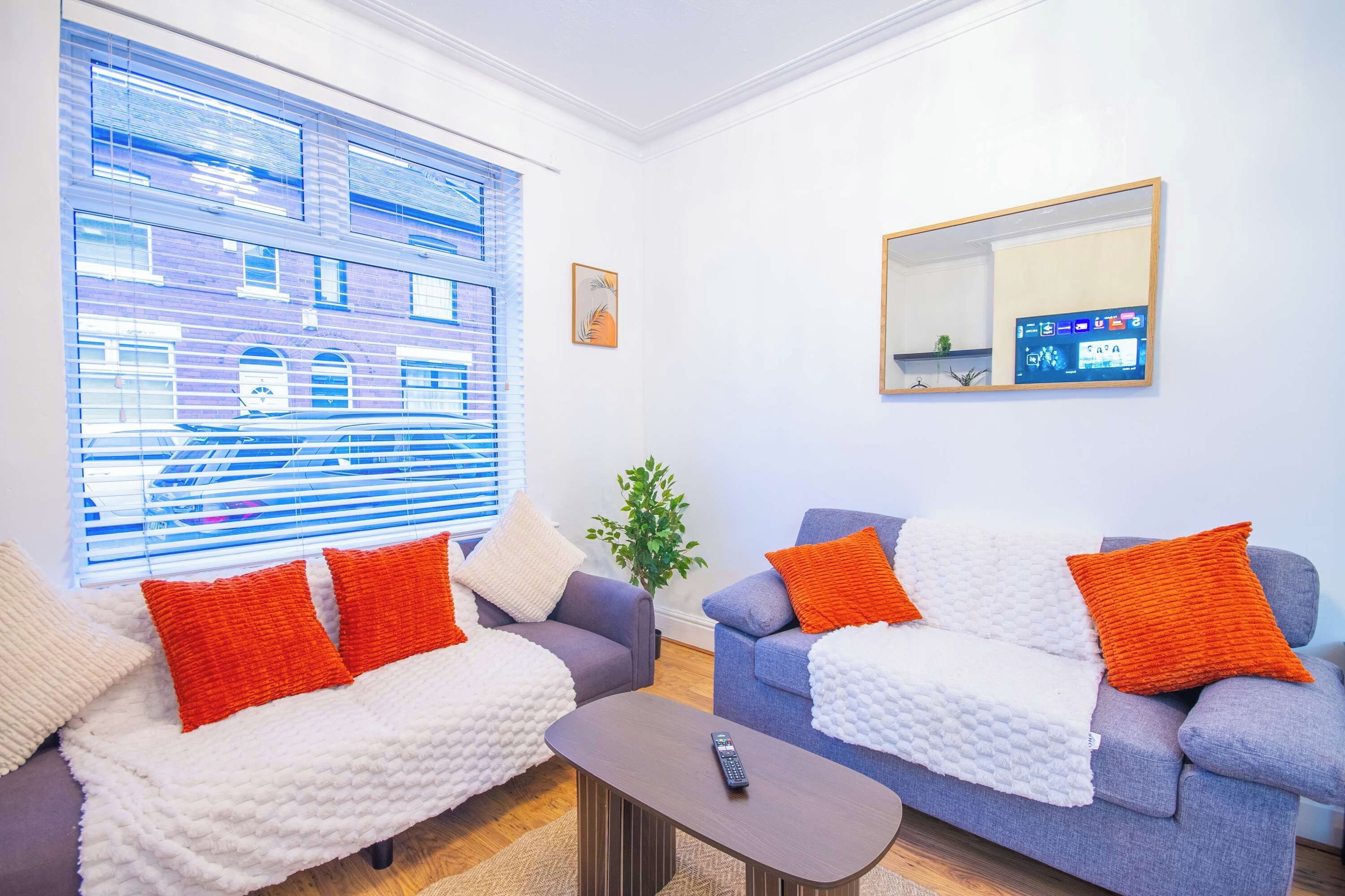 A modern living room with two sofas, a coffee table, and a TV mounted on the wall.