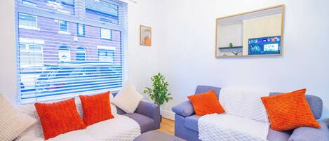 Una sala de estar moderna con dos sofás, una mesa de centro y un televisor montado en la pared.