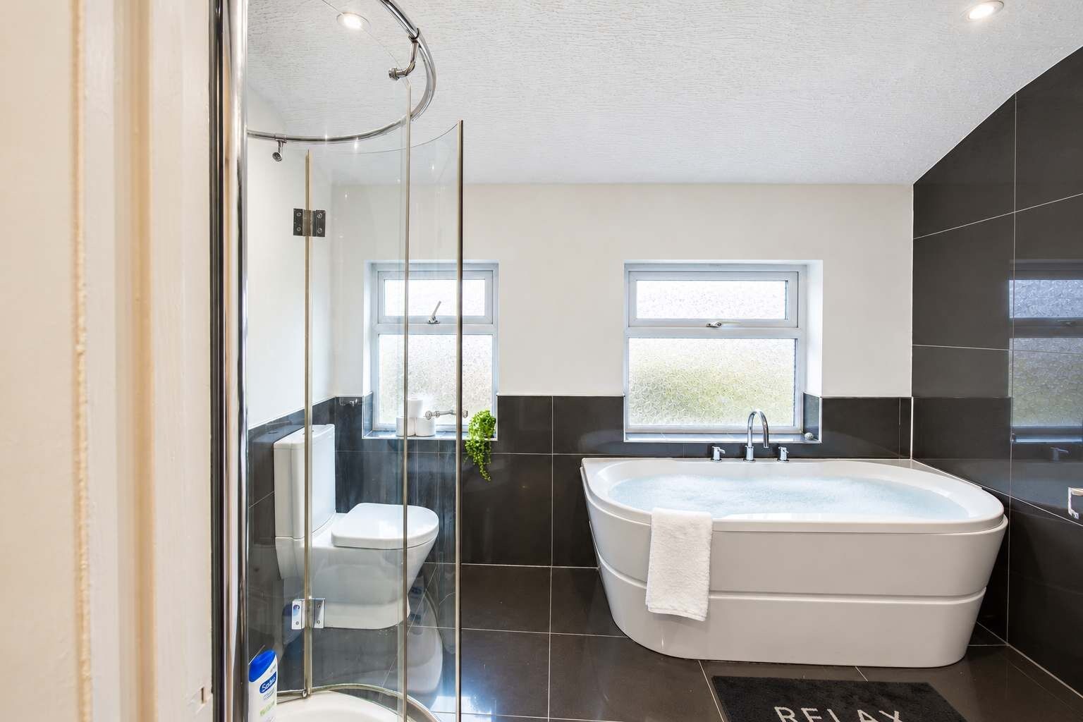 A modern bathroom with a freestanding bathtub, a toilet, and a shower enclosure.