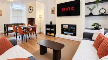 A living room with a foosball table, a flat-screen TV, and a bookshelf.