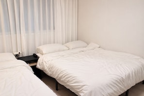 A hotel room with a bed, a bedside table, and a window with curtains. - [SOYO] Serene 2-bedroom apartment with AC in vibrant Seoul (Mapo-gu)