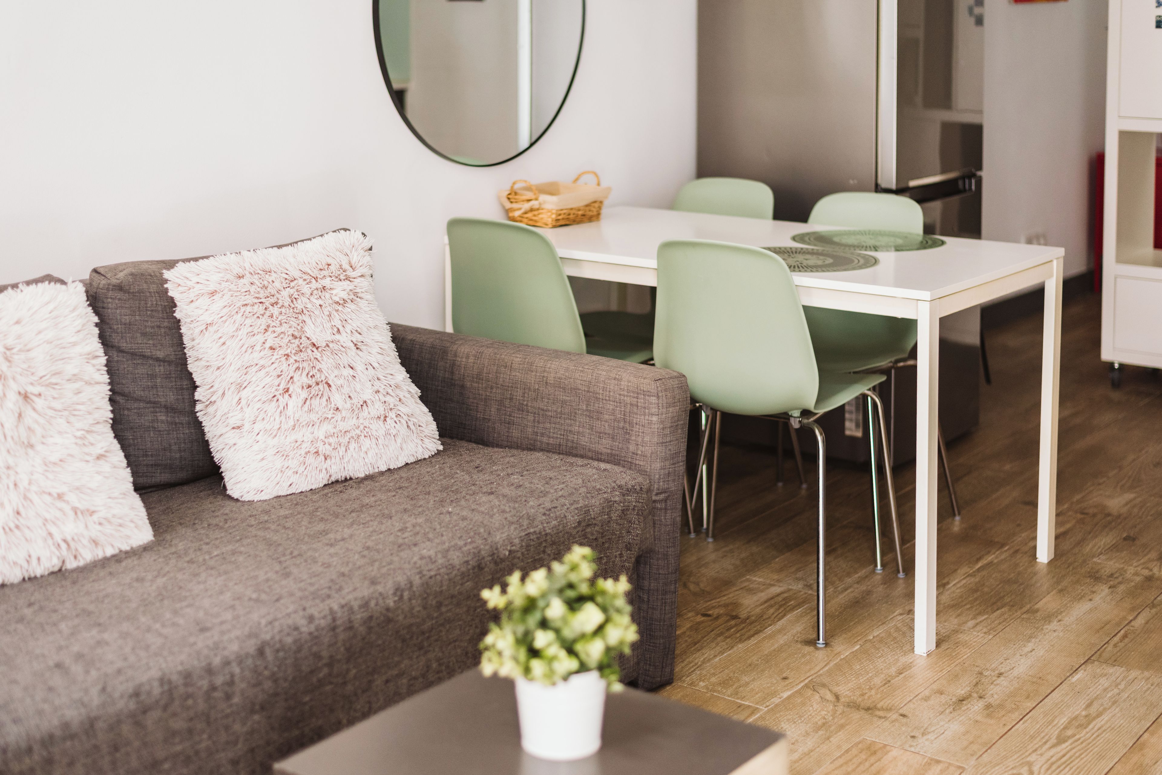 Una sala de estar moderna con un sofá marrón, sillas verdes y una mesa blanca.