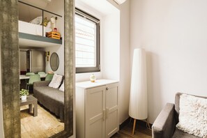 Ein kleines Zimmer mit Etagenbett, Schreibtisch, Stuhl, Schrank und Fenster.