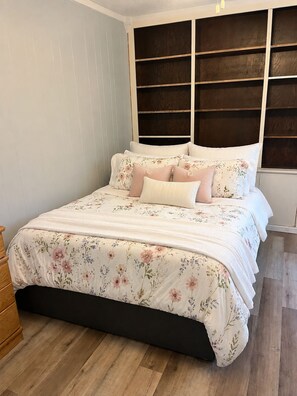 A bedroom with a bed, wooden dresser, and a headboard with shelves. - Cozy Studio Style Private Guest House (Banning)