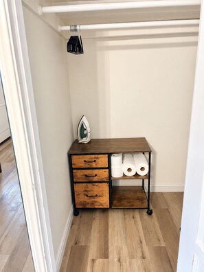 A closet with a wooden dresser, a hanging rack, and a white door.
