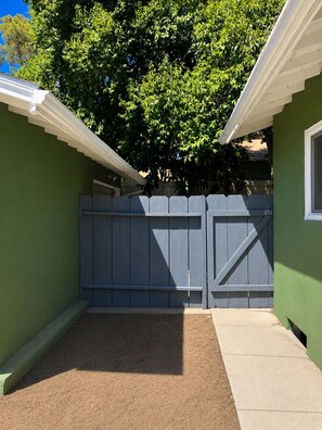 A gated entryway with a wooden fence, a concrete pathway, and a green wall. - Cozy Studio Style Private Guest House (Banning)