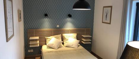 A bedroom with a bed, bedside lamps, a headboard, and a wall with a geometric pattern.