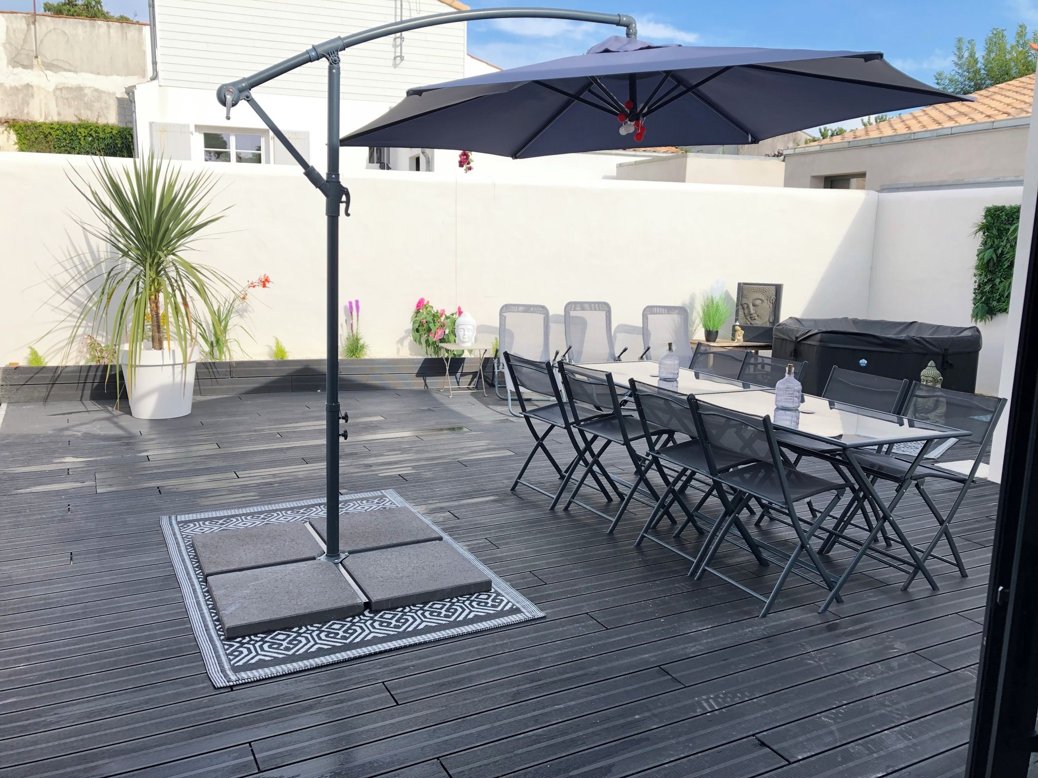 An outdoor patio with a dining table, chairs, a grill, and a large umbrella.