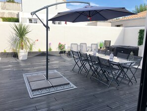 An outdoor patio with a dining table, chairs, a grill, and a large umbrella. - Maison de charme au coeur du village de l'Houmeau (L'Houmeau)