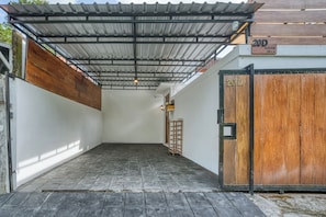 A covered outdoor area with a tiled floor, a wooden door, and a metal roof structure. - Stylish 3BR Pool Villa in Canggu, Bali (Bali)